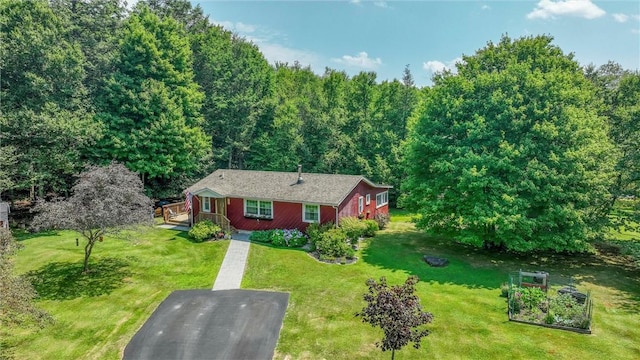 view of front of house featuring aphalt driveway, a wooden deck, and a front yard