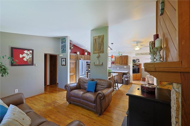 living room with light wood-style floors, a ceiling fan, and vaulted ceiling