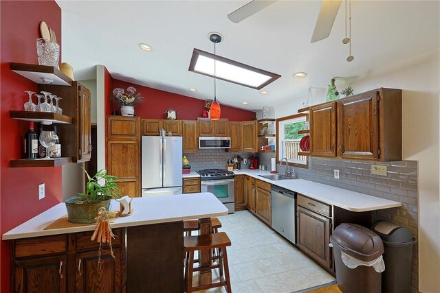 kitchen featuring open shelves, vaulted ceiling with skylight, appliances with stainless steel finishes, and a peninsula