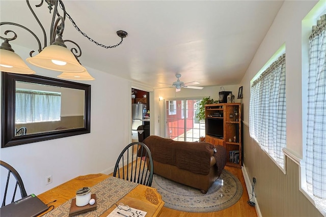 dining space with wood finished floors, a ceiling fan, and baseboards