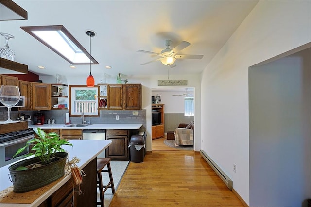 kitchen featuring oven, a baseboard radiator, light countertops, a skylight, and a sink