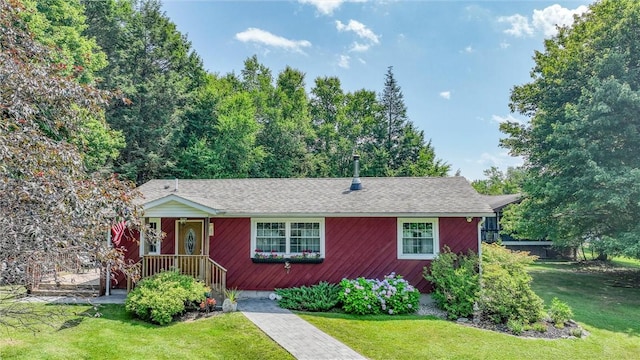 ranch-style house featuring a shingled roof and a front lawn