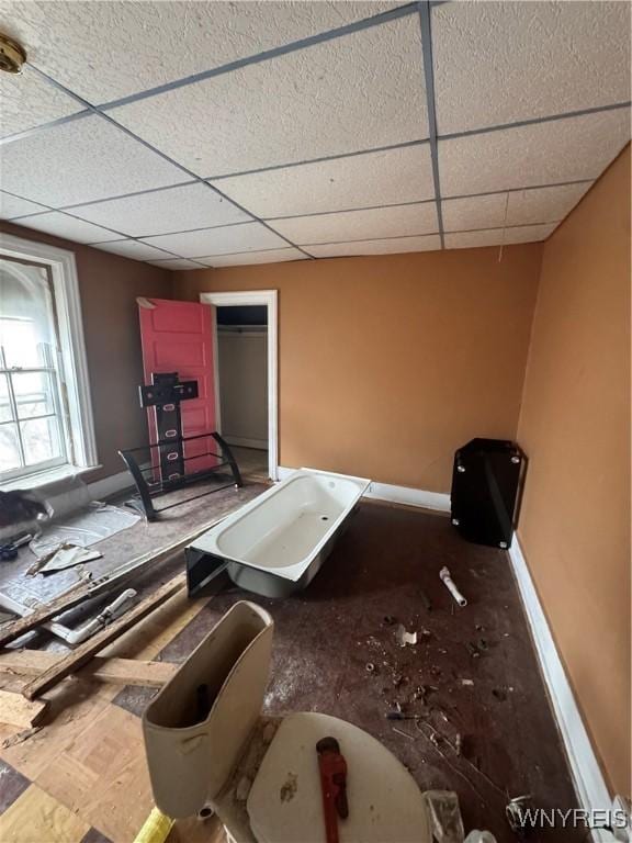 interior space featuring a paneled ceiling and baseboards