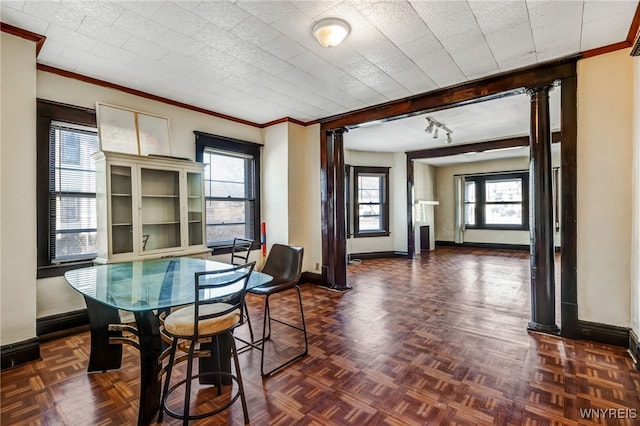 dining area with decorative columns, baseboards, and crown molding