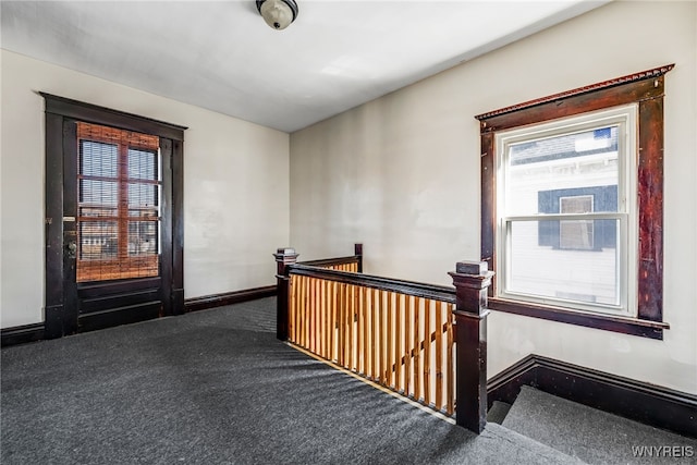 hallway featuring an upstairs landing, baseboards, and carpet