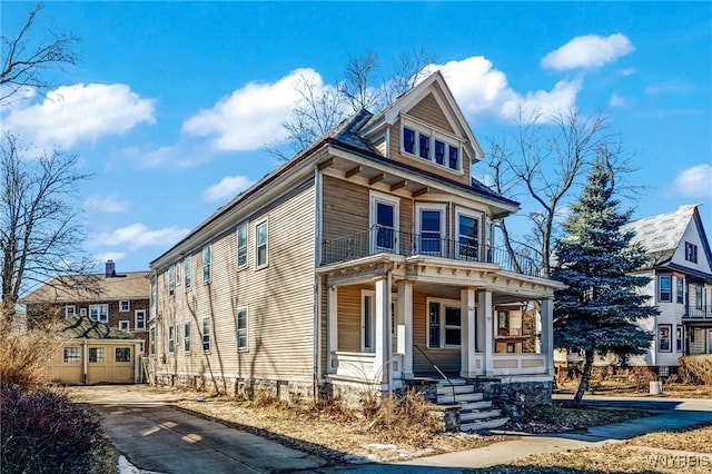 view of front of house featuring a garage, a balcony, covered porch, and driveway