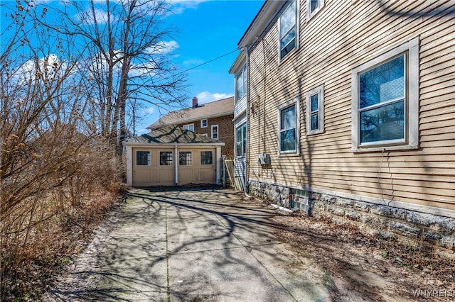 view of home's exterior with an outbuilding and concrete driveway