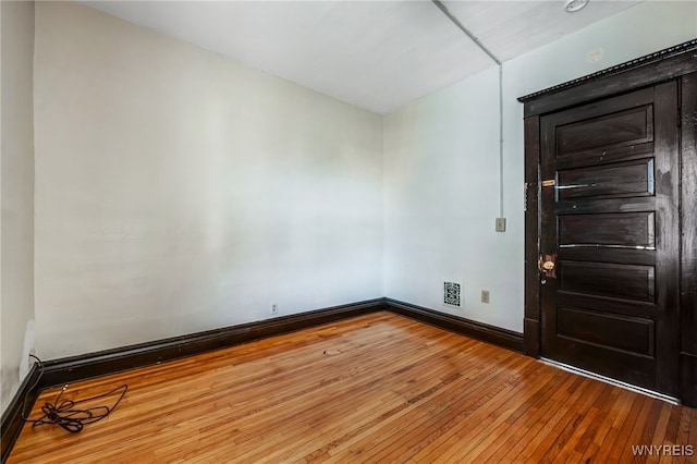 empty room featuring baseboards and wood-type flooring