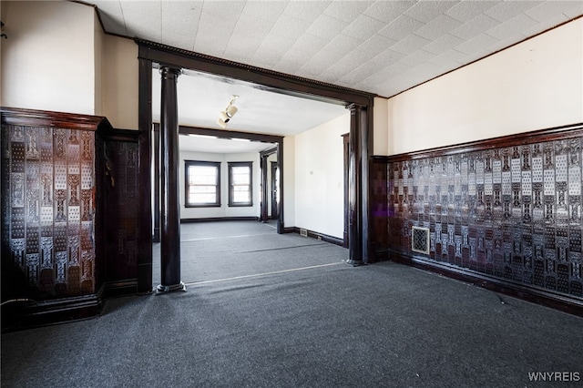 hallway featuring decorative columns and carpet