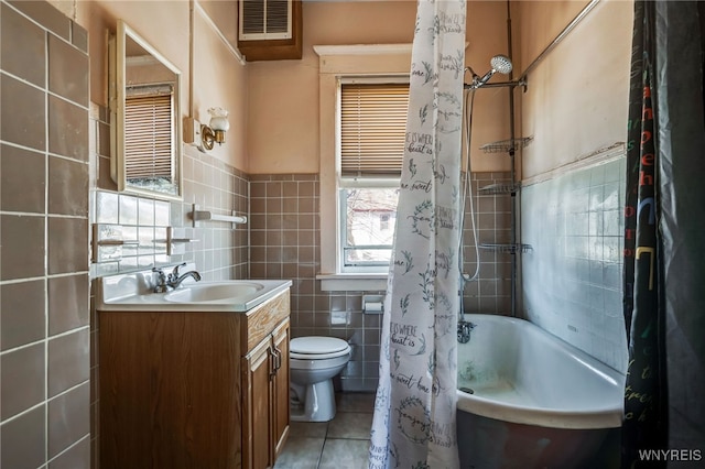 bathroom featuring vanity, visible vents, tile walls, toilet, and tile patterned floors