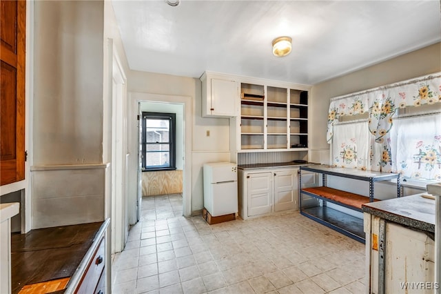 kitchen with dark countertops, white cabinets, and freestanding refrigerator