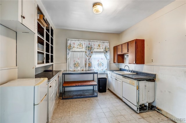 kitchen with white appliances, white cabinets, a wainscoted wall, and a sink