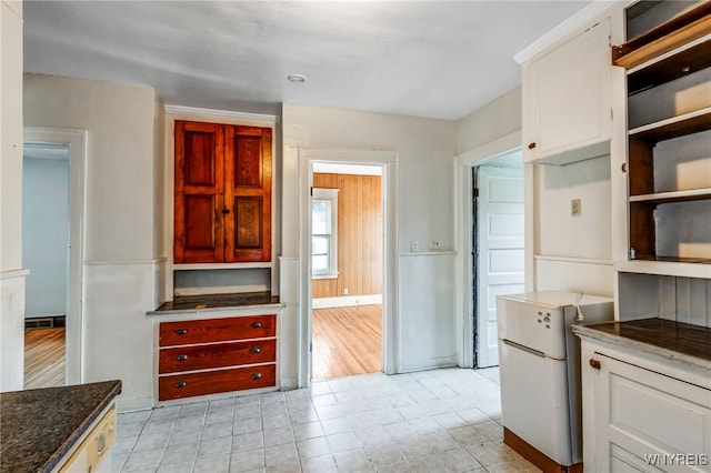 kitchen featuring white cabinetry, dark stone counters, open shelves, and freestanding refrigerator