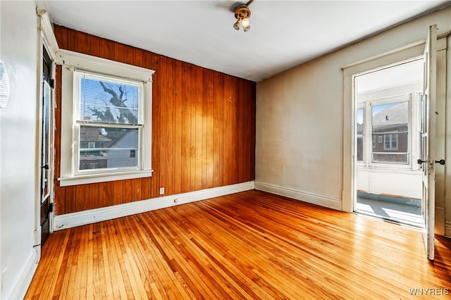 empty room with wood walls, baseboards, and wood-type flooring