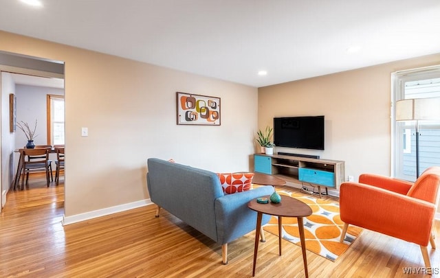 living area featuring baseboards and light wood-type flooring