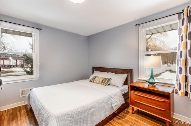 bedroom with visible vents, baseboards, and wood finished floors