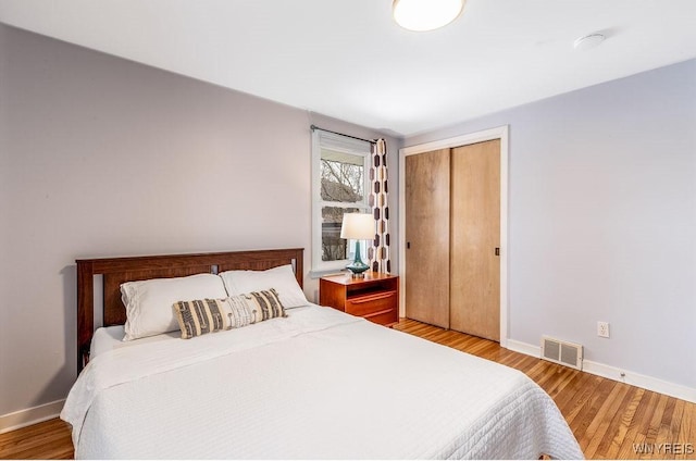 bedroom with visible vents, baseboards, and wood finished floors