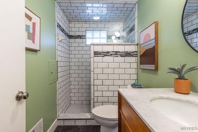 bathroom with visible vents, tiled shower, toilet, and vanity