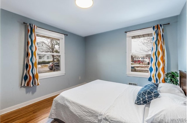 bedroom featuring visible vents, baseboards, and wood finished floors