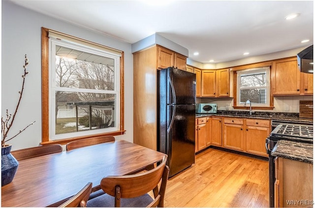 kitchen with light wood finished floors, white microwave, range with gas cooktop, freestanding refrigerator, and a sink