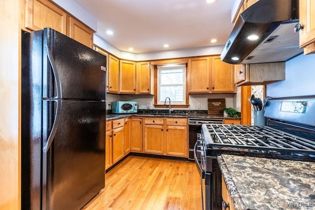 kitchen featuring stainless steel range with gas stovetop, dishwashing machine, island exhaust hood, freestanding refrigerator, and a sink