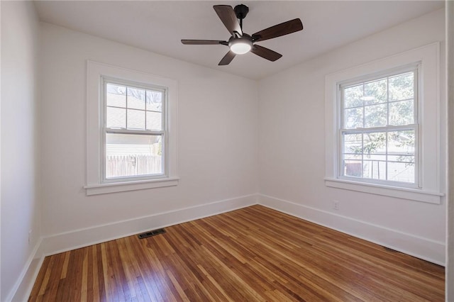 unfurnished room with hardwood / wood-style floors, a healthy amount of sunlight, visible vents, and baseboards