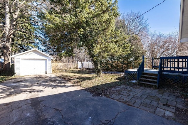 view of yard with an outbuilding, a deck, driveway, fence, and a garage