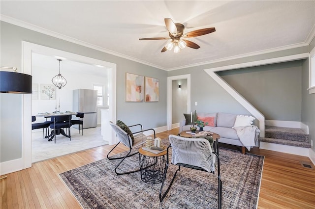 living room with crown molding, stairway, and light wood-type flooring