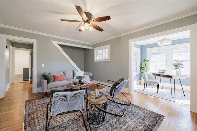 living room with light wood-style flooring, a ceiling fan, crown molding, and baseboards