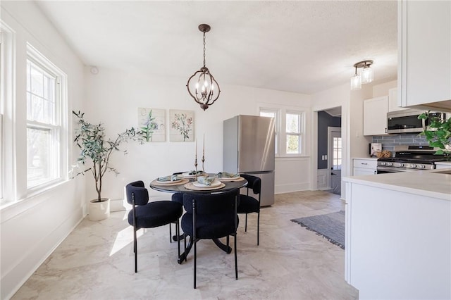 dining area featuring baseboards, marble finish floor, and a chandelier