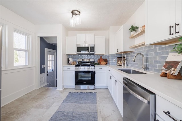 kitchen with a sink, stainless steel appliances, open shelves, and white cabinets