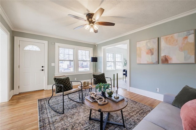 living room with crown molding, light wood-style flooring, baseboards, and a textured ceiling