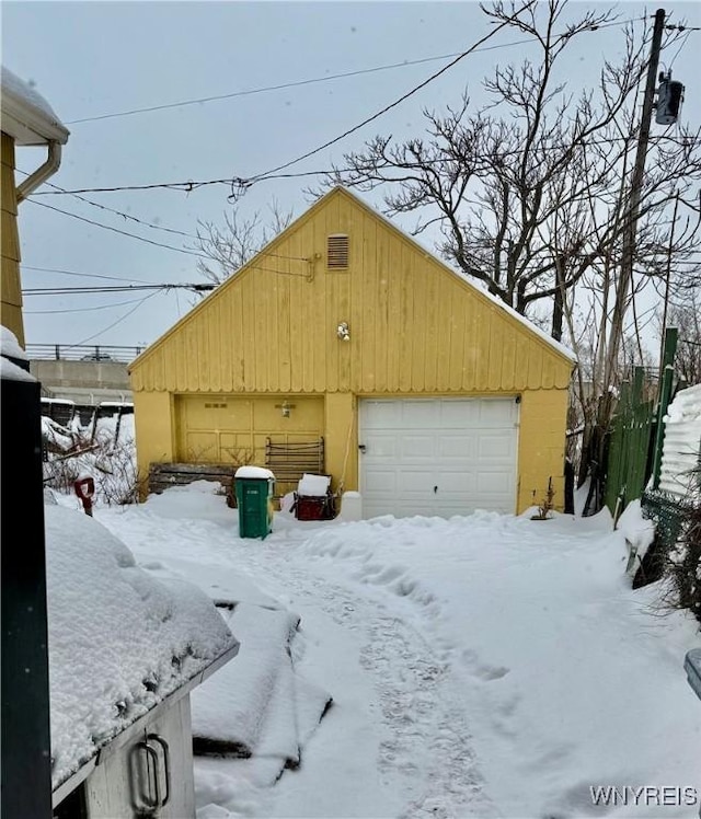 snow covered garage with a detached garage