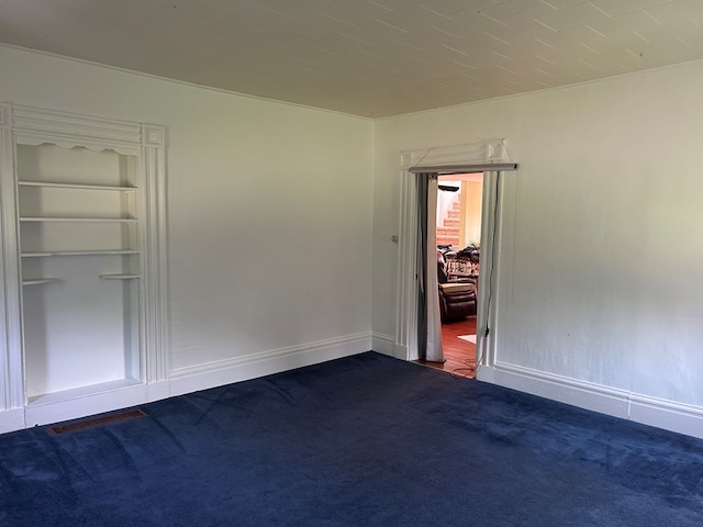 unfurnished room with dark colored carpet, baseboards, and built in shelves