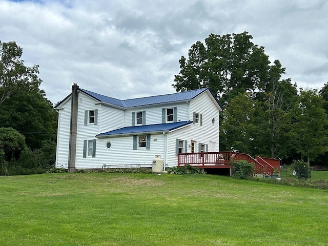 rear view of house featuring a chimney, a lawn, metal roof, and a deck