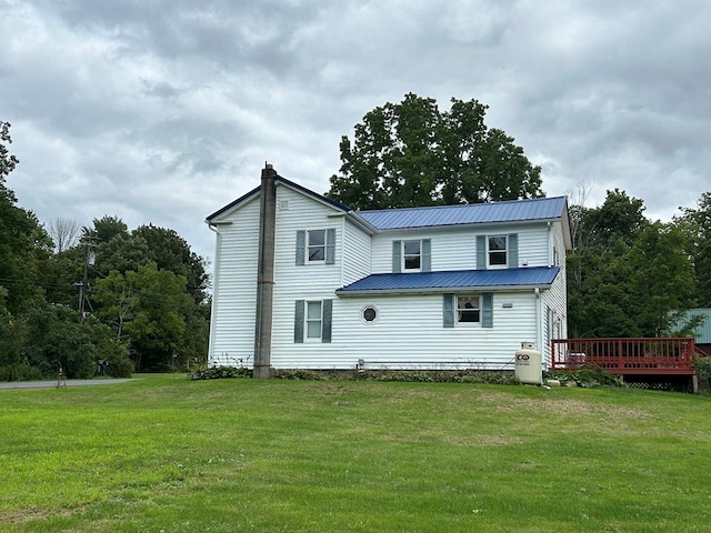 back of house with a wooden deck, a yard, metal roof, and a chimney