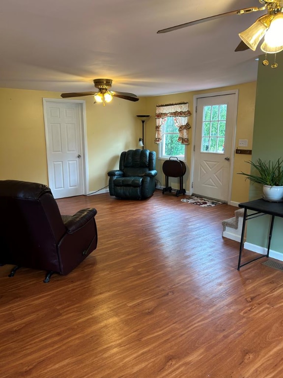 living area featuring baseboards, wood finished floors, and a ceiling fan