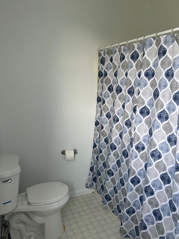 bathroom featuring curtained shower, baseboards, and toilet