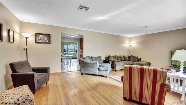 living area featuring crown molding, visible vents, and light wood finished floors