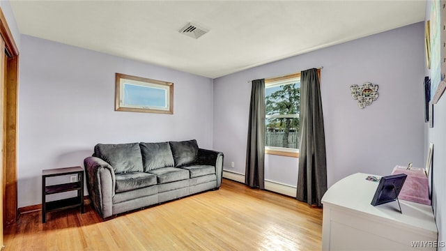 living room featuring baseboards, visible vents, baseboard heating, and light wood-style floors