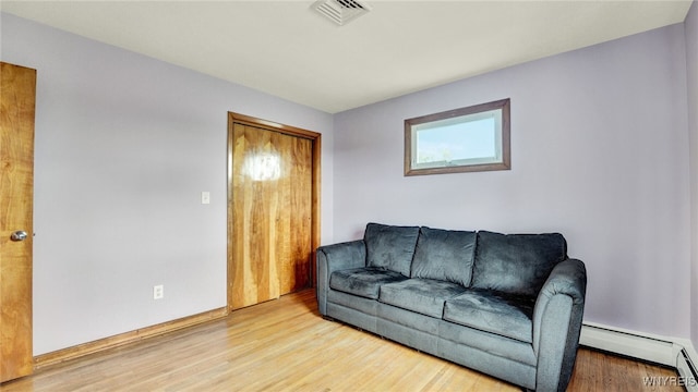 living room with visible vents, baseboard heating, and wood finished floors