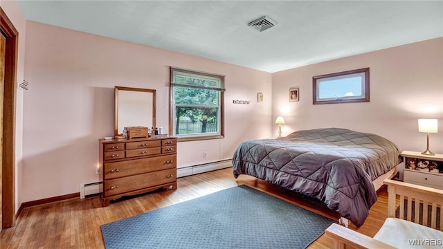 bedroom with light wood finished floors, baseboards, visible vents, and baseboard heating