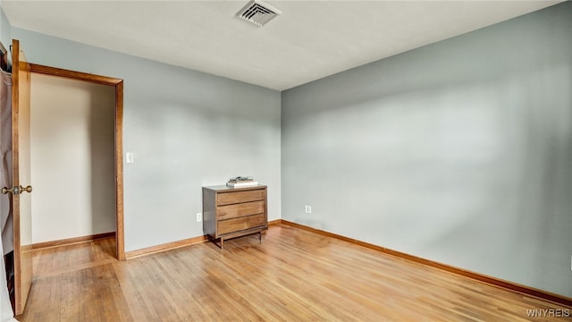 empty room with baseboards, visible vents, and light wood finished floors