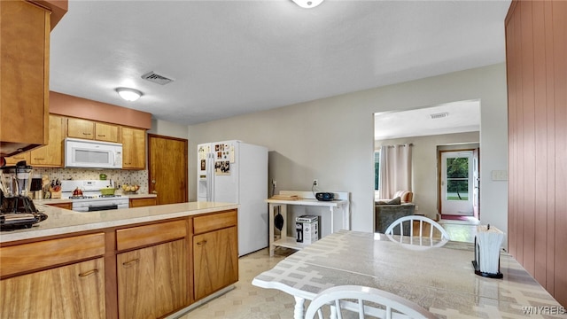 kitchen with white appliances, light floors, visible vents, light countertops, and tasteful backsplash