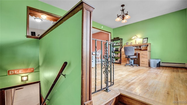 home office with a baseboard heating unit, a notable chandelier, wood finished floors, and baseboards