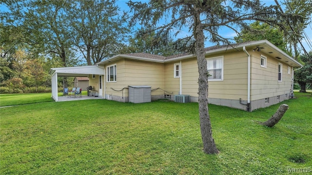 back of property featuring an attached carport, a patio, cooling unit, crawl space, and a lawn