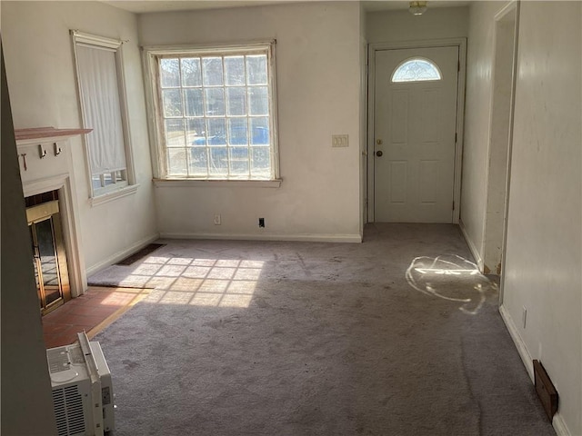 foyer entrance with a fireplace with flush hearth, baseboards, visible vents, and carpet flooring