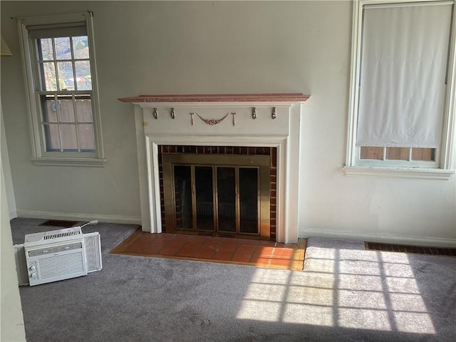 room details featuring visible vents, a brick fireplace, baseboards, a wall unit AC, and carpet flooring