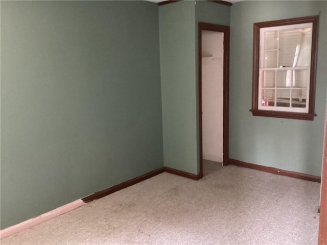 empty room featuring baseboards and light colored carpet