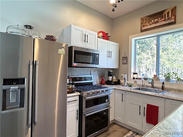 kitchen featuring appliances with stainless steel finishes, white cabinetry, and a sink